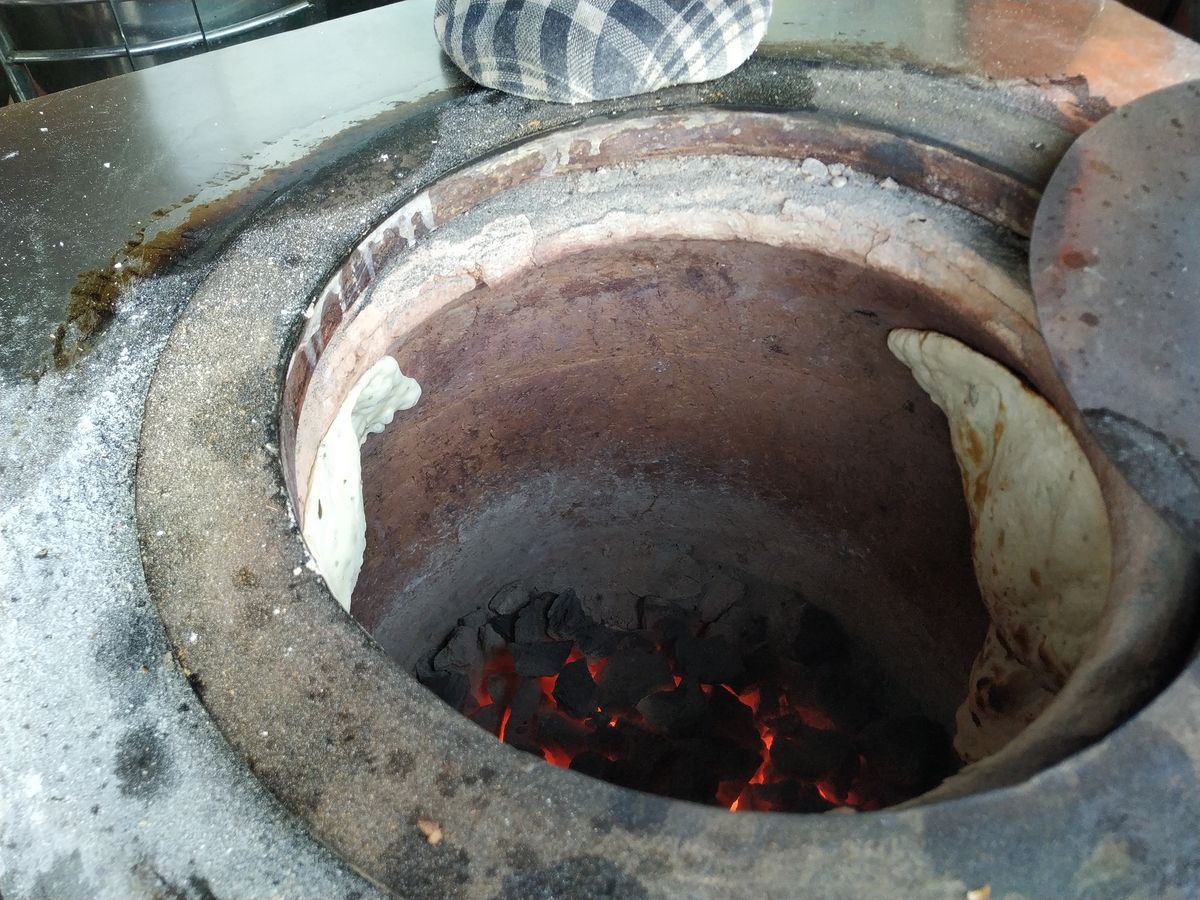 Fresh naan bread baking on the clay walls of a traditional tandoor